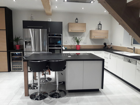 Cuisine en laque blanc mat, pieds d'îlot et crédences en chêne massif, plan de travail stratifié, meubles hauts en aggloméré chêne.